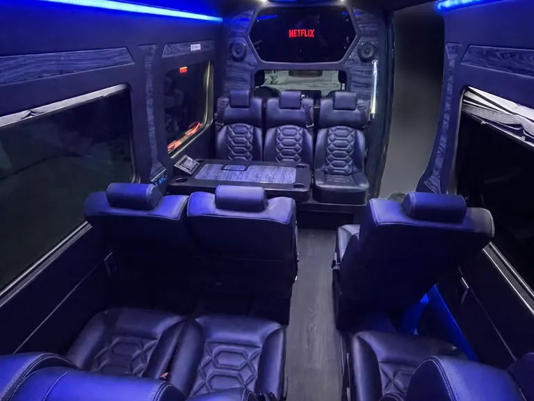 Executive Sprinter cabin with black leather seating and blue ambient lighting