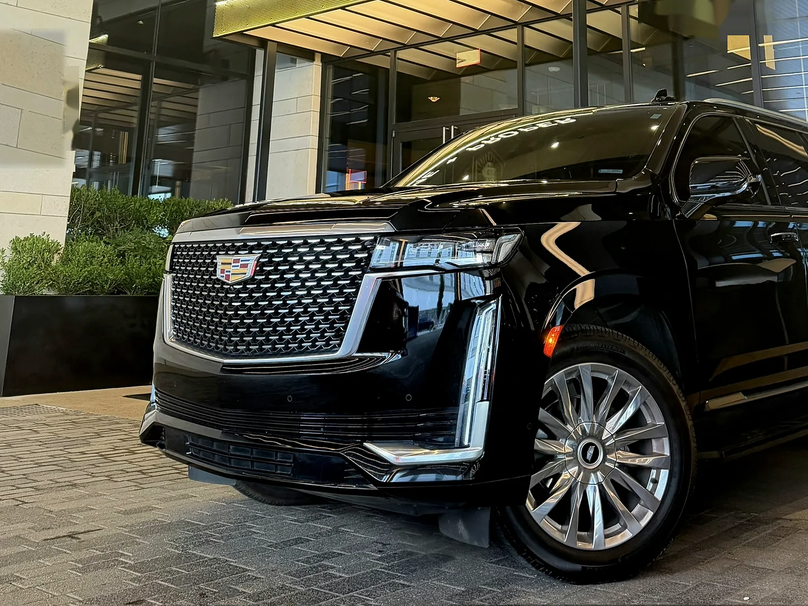Black Cadillac Escalade SUV at night under warm gold entrance lighting — My Nashville Driver private black car service