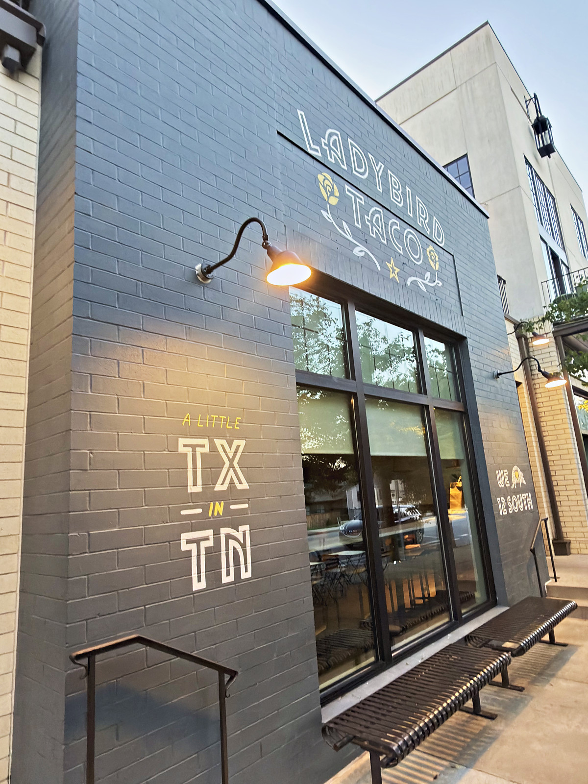 Ladybird Taco storefront with 'A Little TX in TN' painted on gray brick in 12 South, Nashville