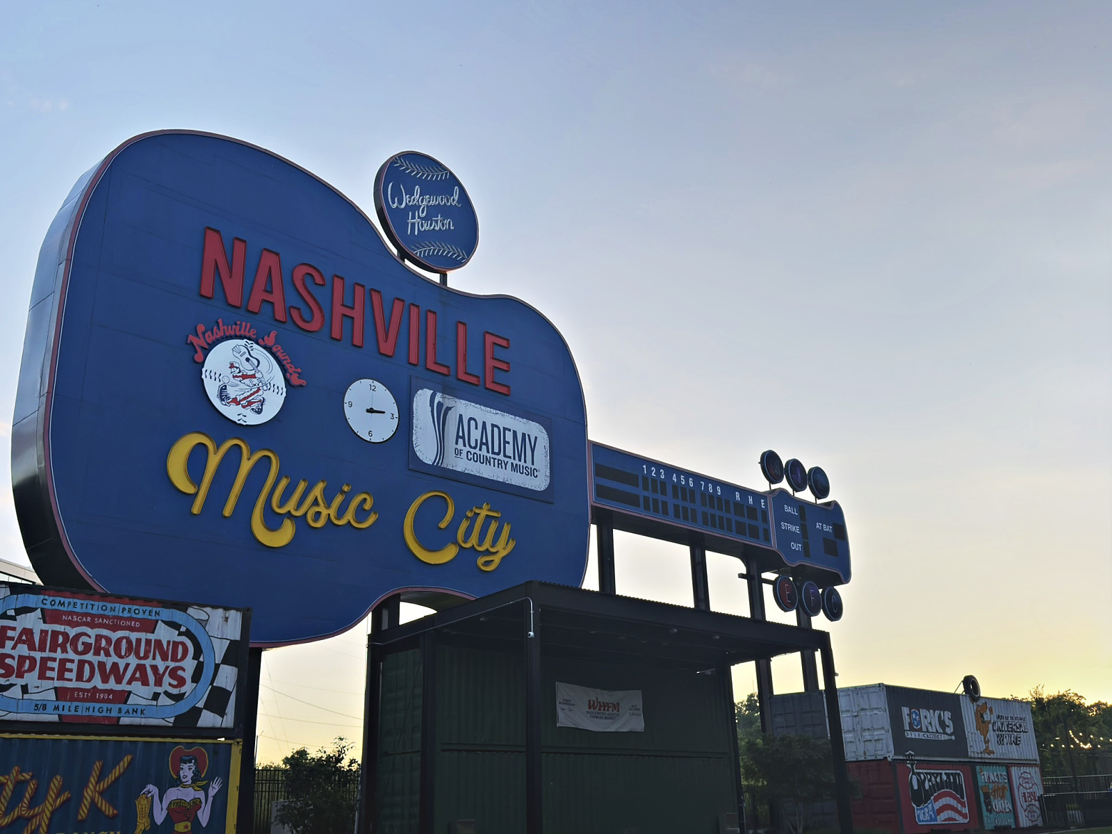 The blue guitar-shaped Nashville Music City sign lit against a sunset sky at the Nashville Fairgrounds