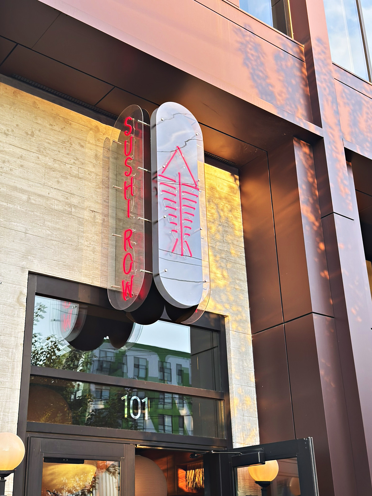 The vertical neon Sushi Row sign with a pink fish motif above the restaurant entrance in Wedgewood-Houston, Nashville