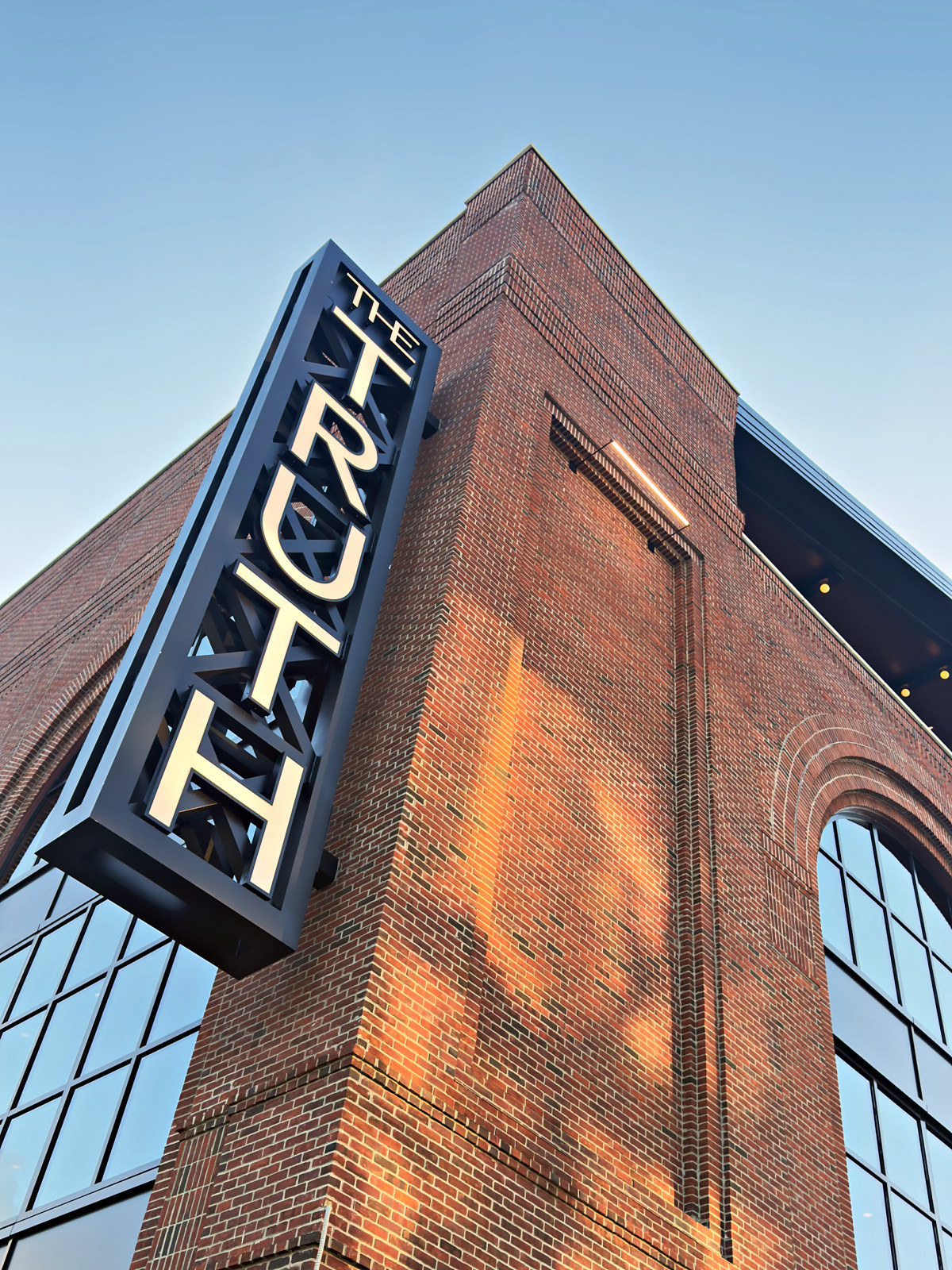 The vertical blade sign for The Truth mounted on the corner of a brick building in Wedgewood-Houston