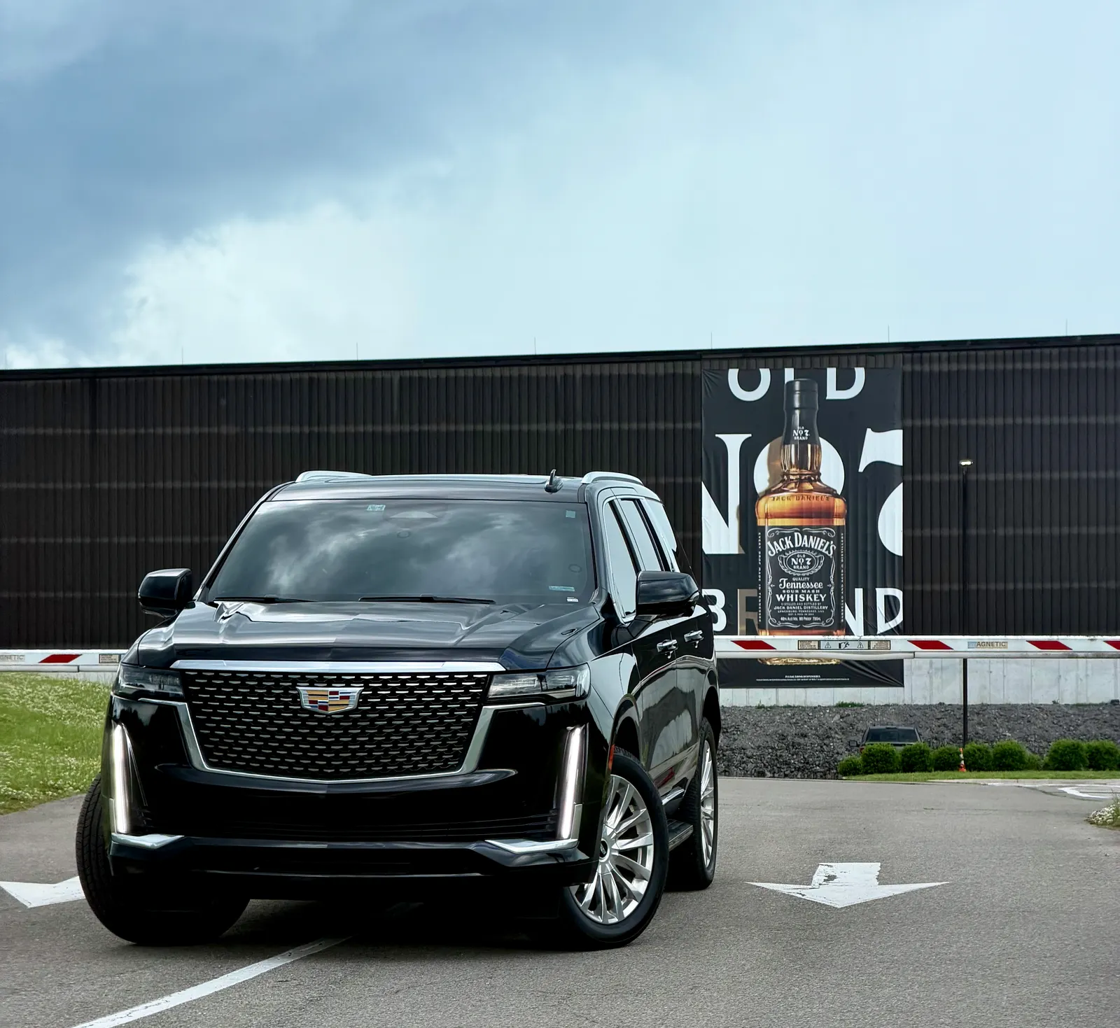 Black SUV outside a dark building displaying a Jack Daniel’s bottle banner