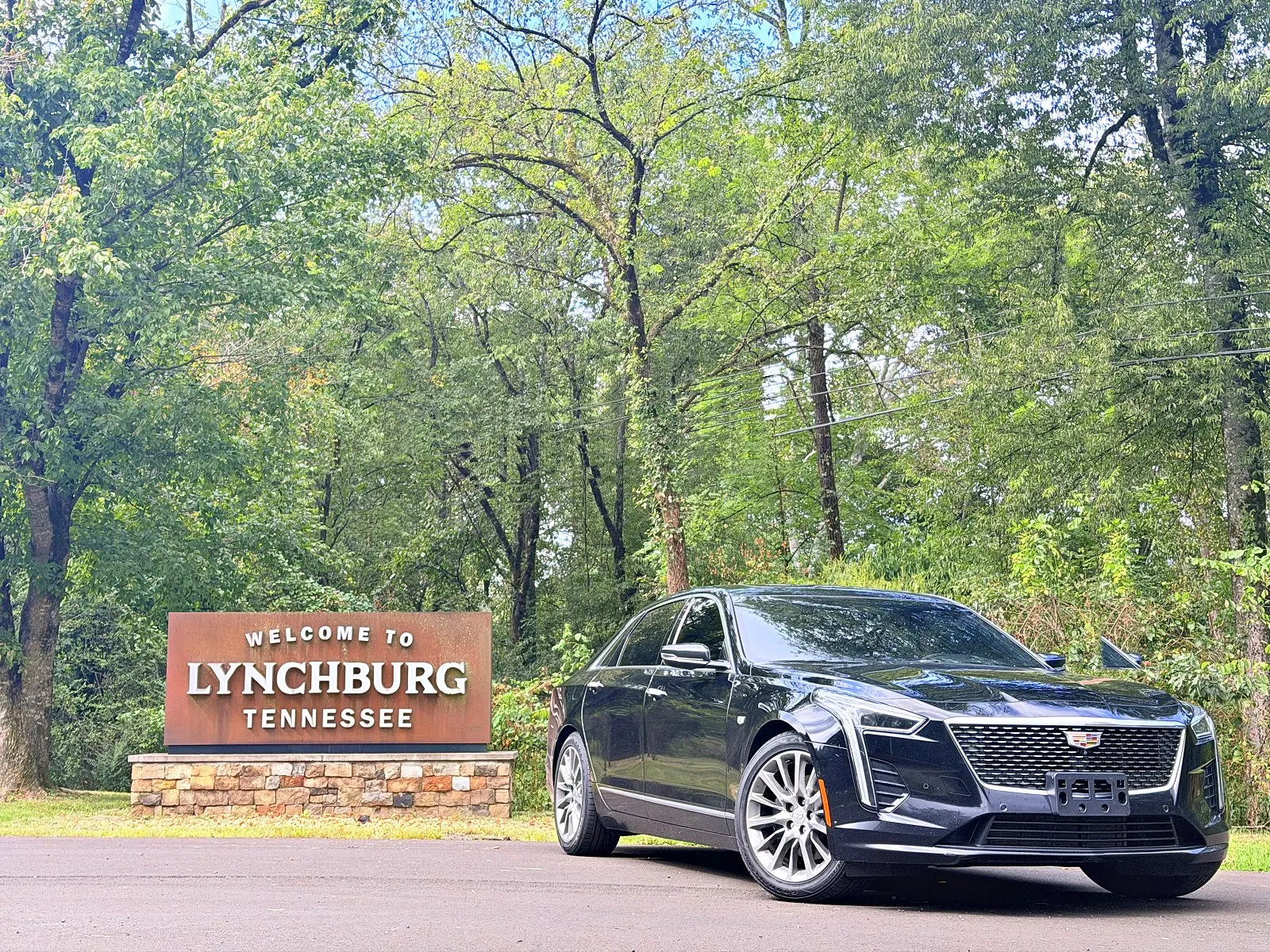 Black Cadillac sedan beside the Welcome to Lynchburg, Tennessee sign
