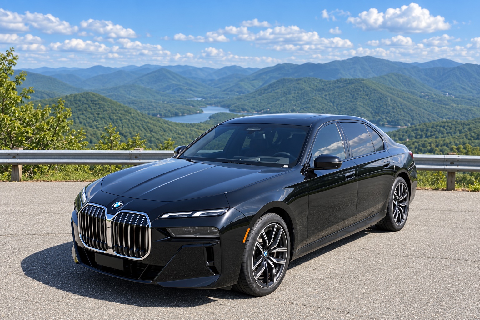 Black BMW 740 sedan parked at a mountain overlook, viewed from the front and side.
