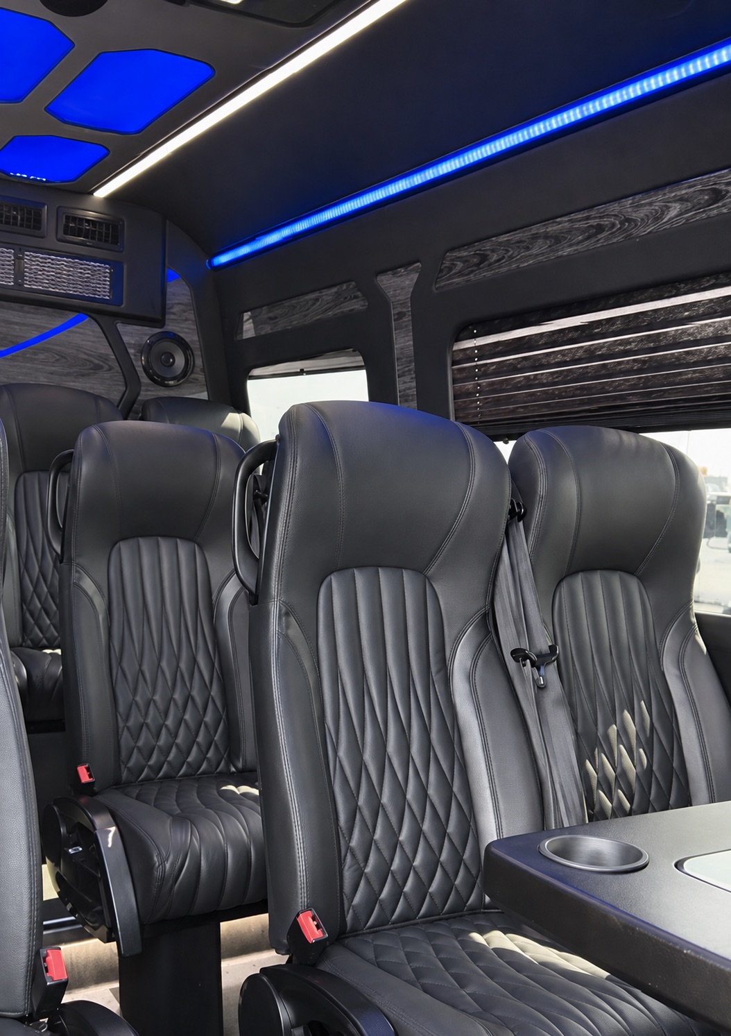 Executive Sprinter interior with black quilted captain’s chairs and ambient ceiling lighting.
