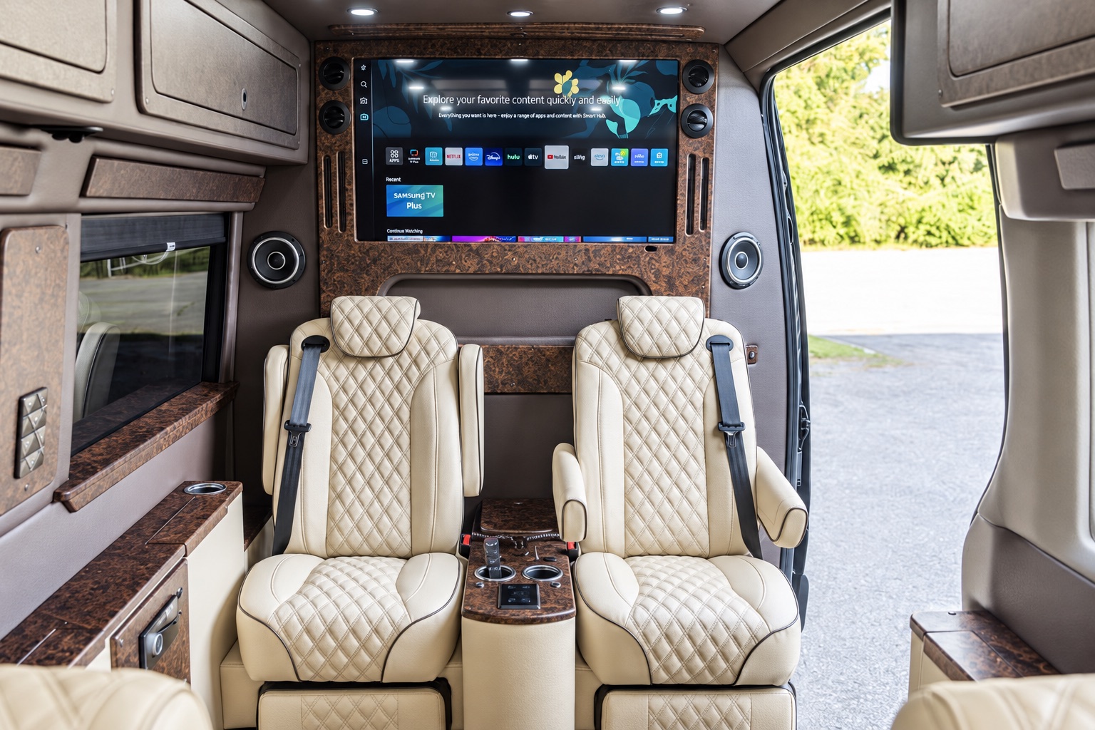 Jet Sprinter interior with cream quilted reclining seats, a center console and a large screen.