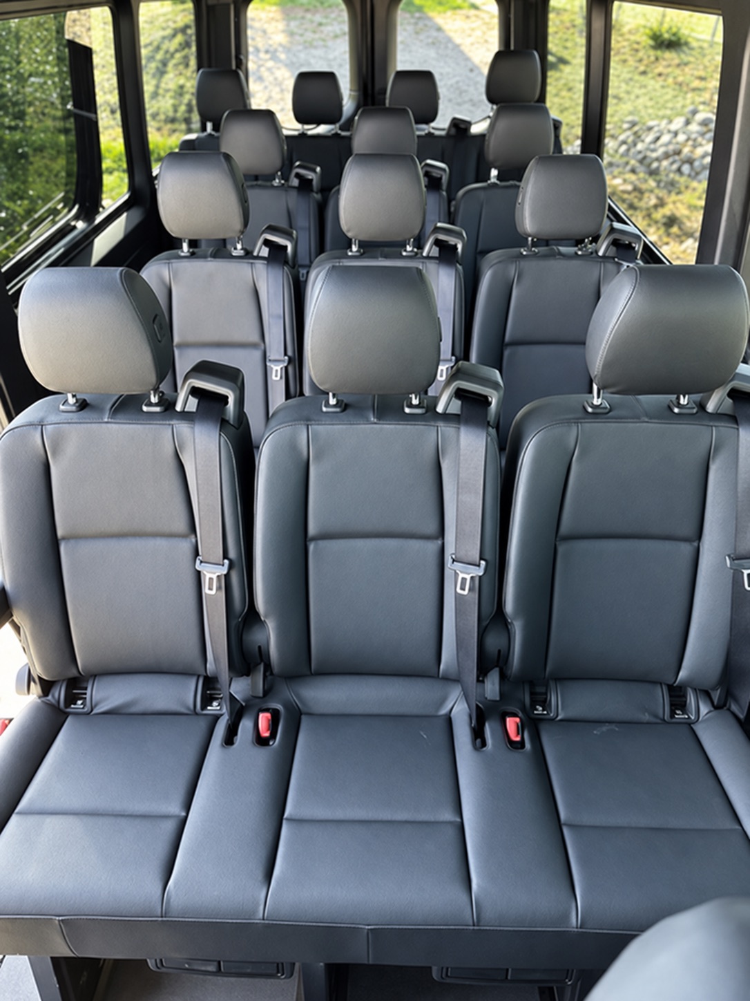 Passenger Sprinter interior with rows of black seats and individual headrests.