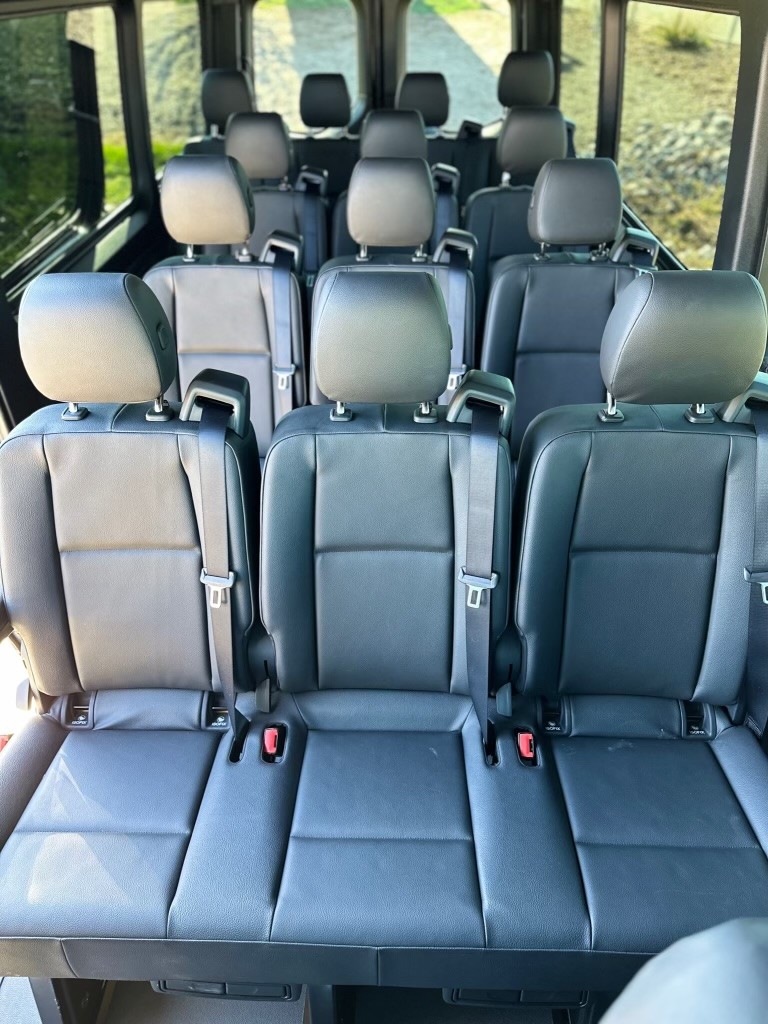 Actual Passenger Sprinter cabin with rows of individual dark seats, headrests and seat belts.